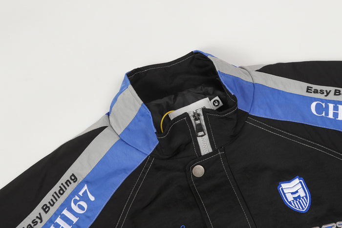 Close-up of the black jacket collar, blue shoulder stripe, snap placket, and shield patch