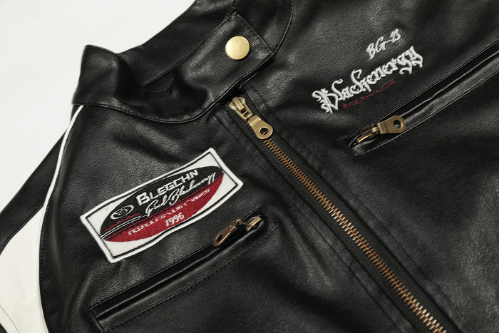 Close-up of the jacket front showing the snap collar, gold main zipper, chest patch and zippered pockets