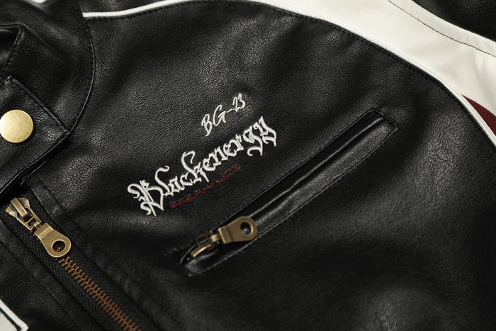 Close-up of black PU leather jacket chest with white embroidered lettering and a horizontal zippered pocket