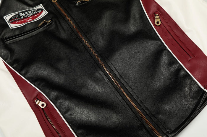 Close-up of the jacket front showing the gold center zipper, black panel and burgundy zippered side panels