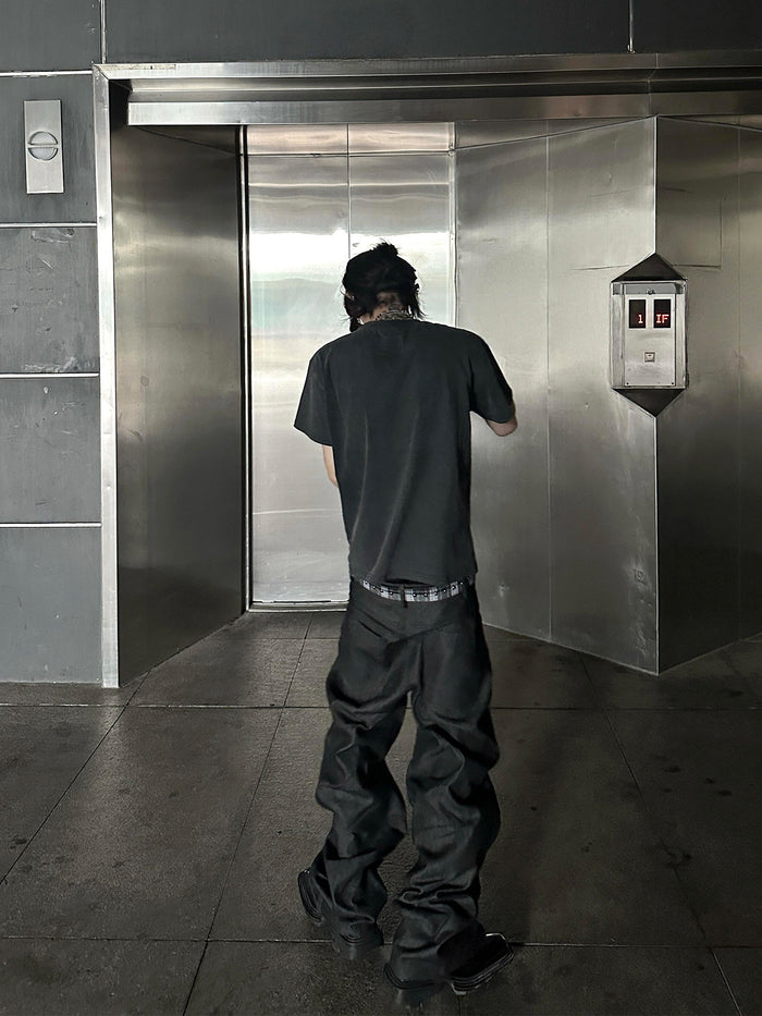 Rear model view wearing loose black straight-leg jeans with side snaps visible near the outer hems