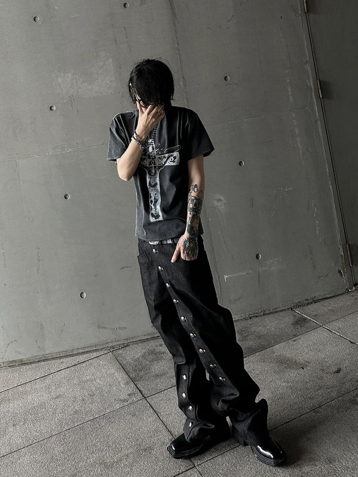 Front angled model view wearing black denim jeans with silver side snap buttons running down the legs