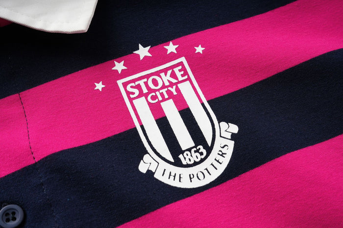Close-up of the white Stoke City crest with stars and 1863 text printed on a hot pink and navy shirt stripe