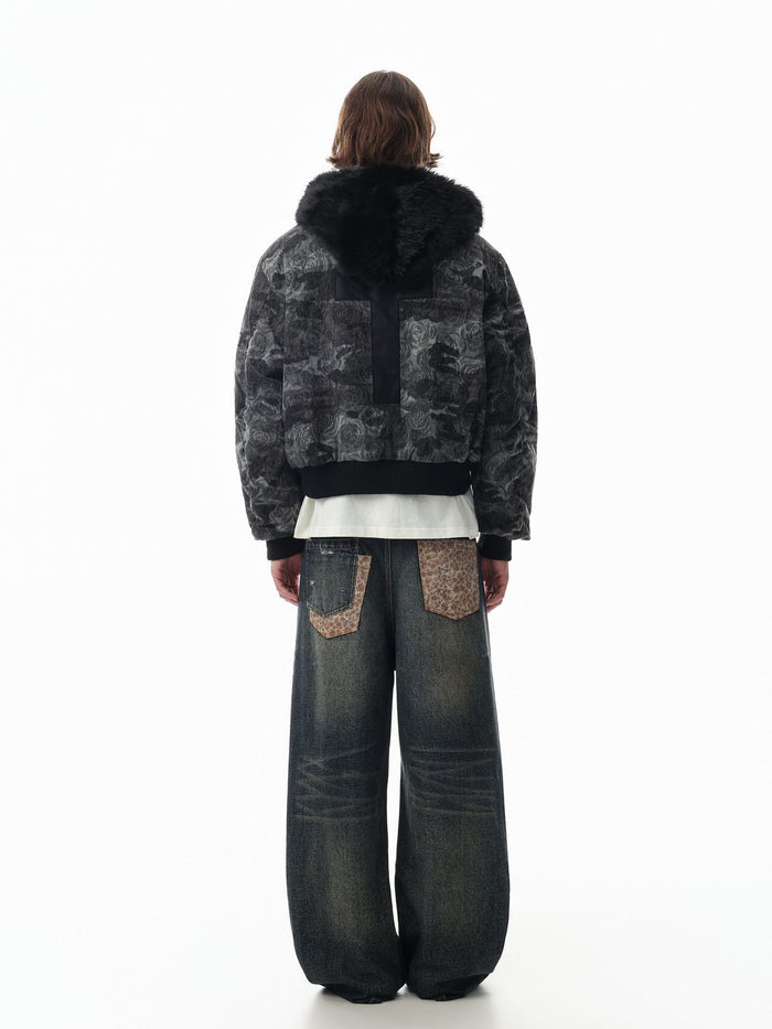 Model wearing the camouflage bomber jacket in a back view, showing the black faux fur collar and ribbed hem