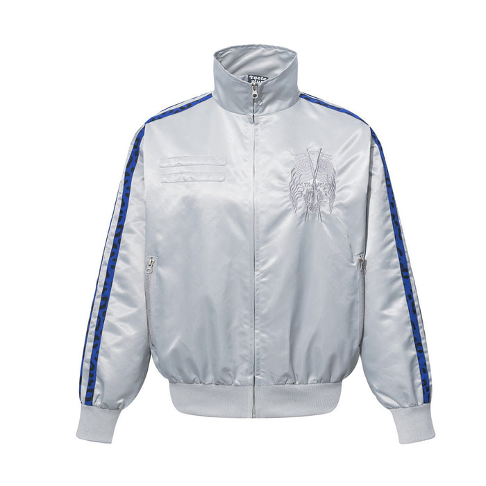 White satin bomber jacket front with stand collar, embroidered chest emblem, zip pockets, and blue leopard stripe tape