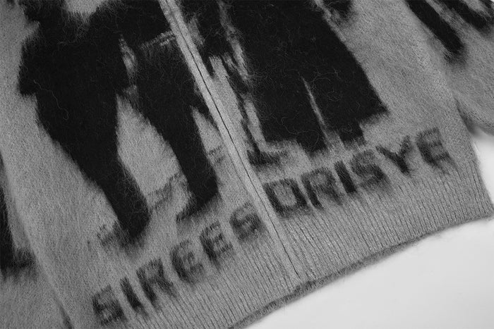 Close-up of the cardigan hem with black shadow figures, printed text, zipper, and ribbed knit trim