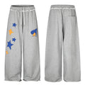 Gray wide-leg sweatpants shown front and back, with blue and orange star appliqués and a rear pocket