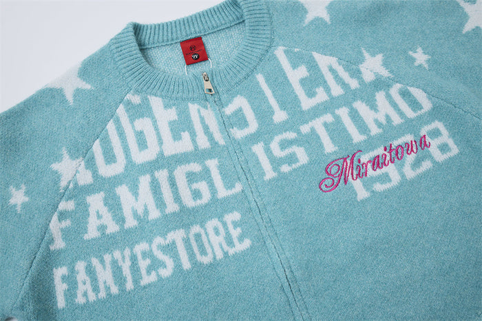 Close-up of turquoise cardigan front showing white jacquard lettering, pink script, stars, and zipper