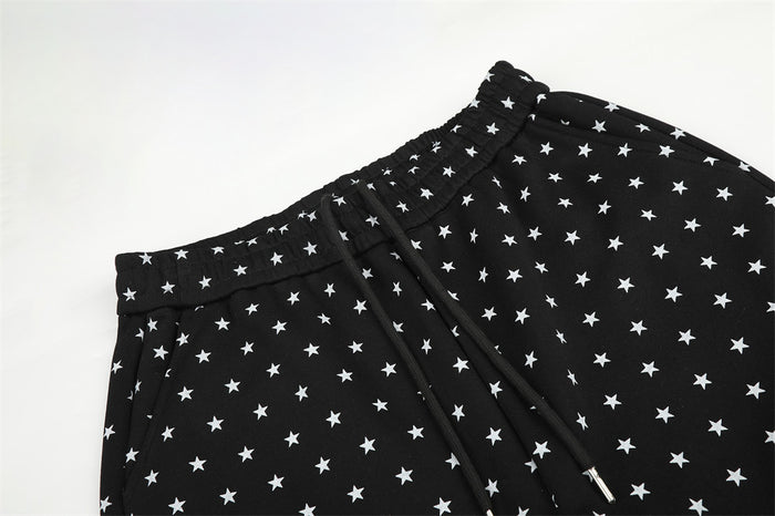 Close-up of black star-print sweatpants showing the elastic waistband and black drawstring