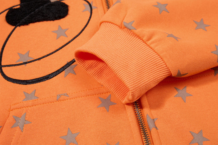 Close-up of orange hoodie ribbed sleeve cuff, gray star print, and front zipper