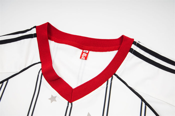 Close-up of the white jersey's red ribbed V-neck collar with black shoulder stripes and gray star print