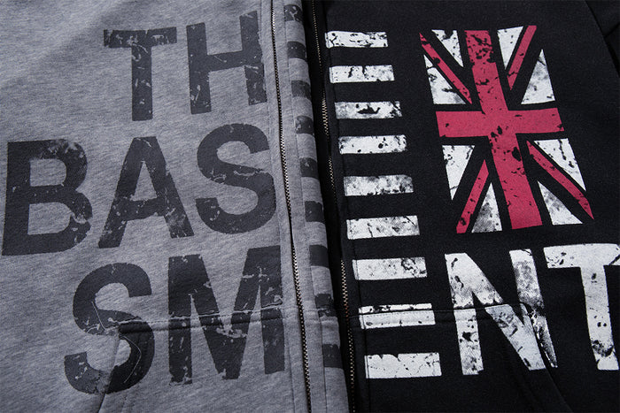Close-up of distressed The Basement lettering and Union Jack graphics across gray and black hoodie fronts