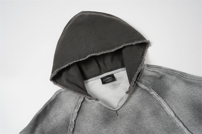 Close-up of the gray hoodie neckline showing its raw-edge hood, inner lining, and sewn label