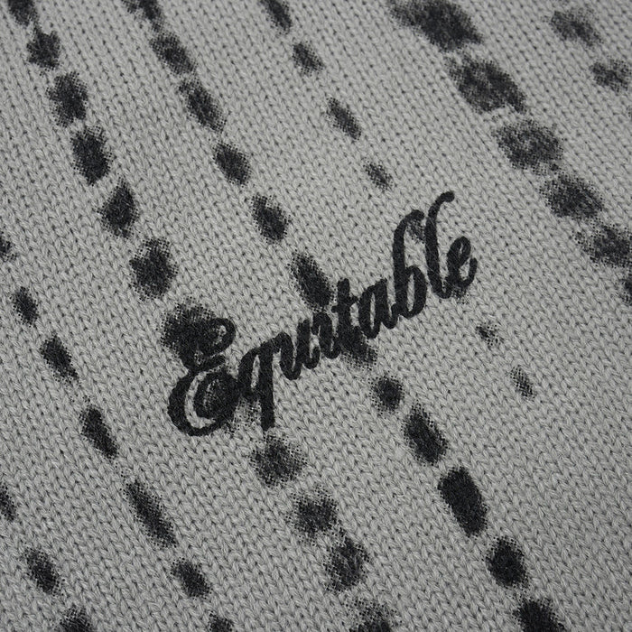 Close-up of a black script logo on gray knit fabric with distressed vertical stripe detailing