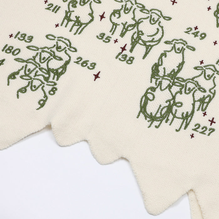 Close-up of the cream vest hem showing sheep graphics, numbered details, and pointed scalloped edging