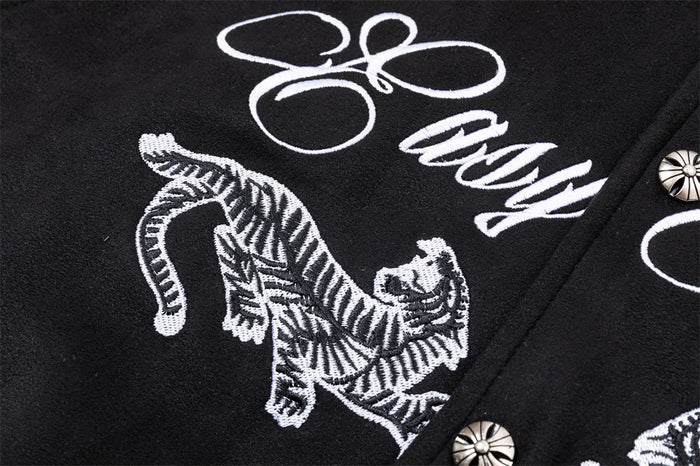 Detailed close-up of a white embroidered tiger graphic and script lettering on the black jacket front