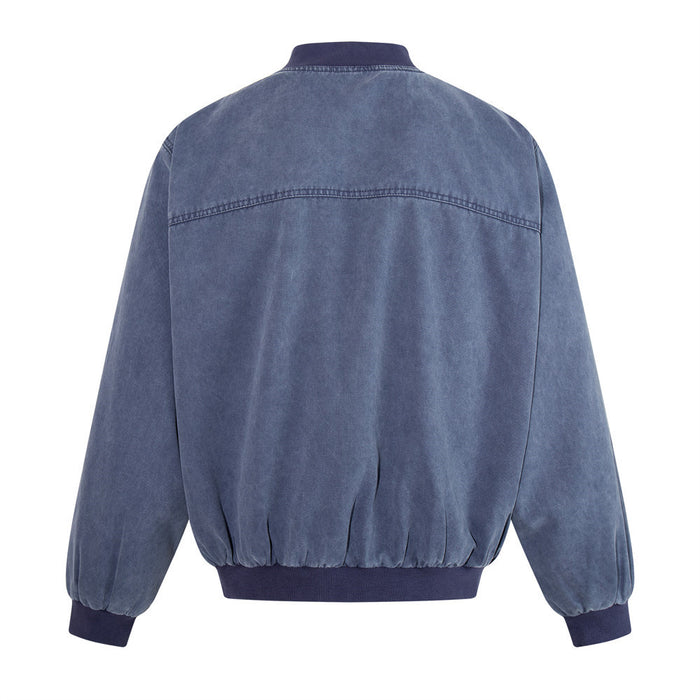 Back view of a washed blue canvas bomber jacket showing the curved shoulder seam, ribbed stand collar and hem