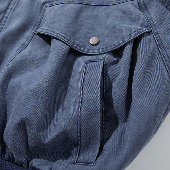 Close-up of a large washed blue canvas jacket pocket with a snap-button flap and reinforced vertical opening