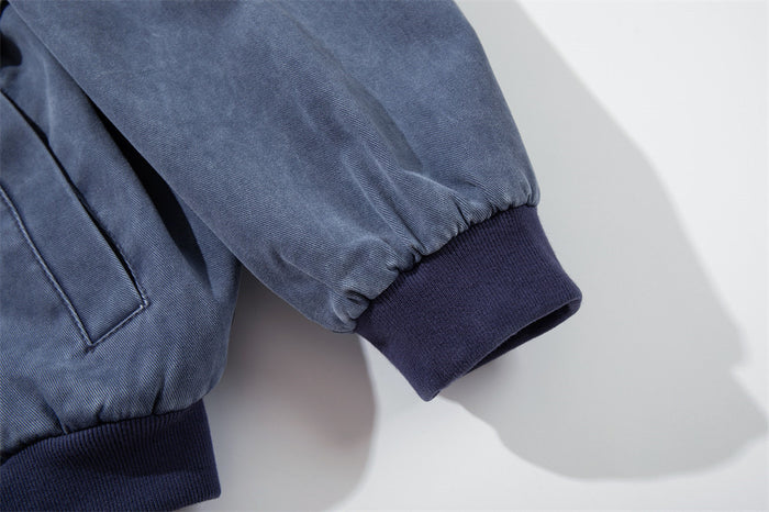 Close-up of the bomber jacket sleeve showing gathered blue canvas, dark ribbed cuff and elasticized seam