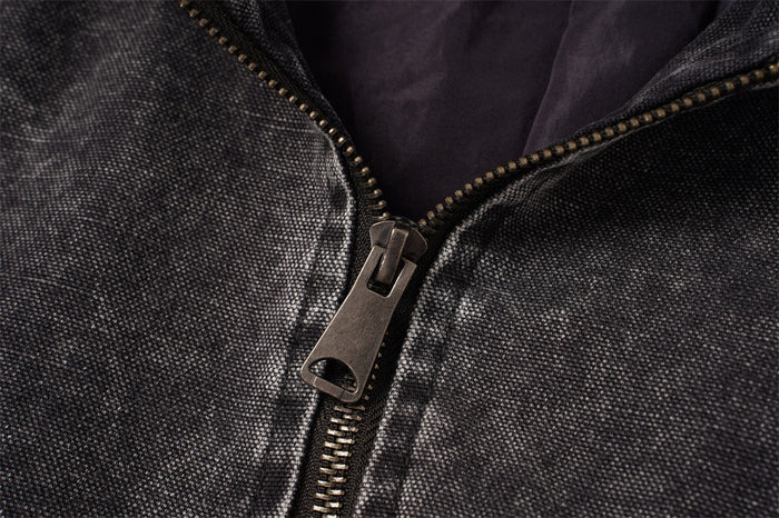 Close-up of the bomber jacket front zipper and metal pull against textured washed charcoal fabric