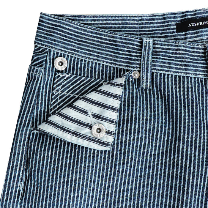 Close-up of a front pocket on blue striped jeans with a buttoned flap and contrasting horizontal stripe lining