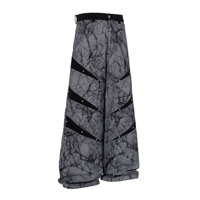 Three-quarter front view of gray baggy wide-leg jeans with crackle print and black studded stripes