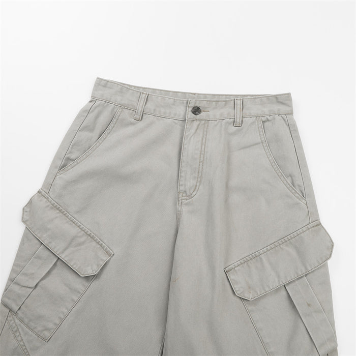 Close-up of light gray cargo pants showing the waistband, button closure, front pockets, and flap cargo pockets