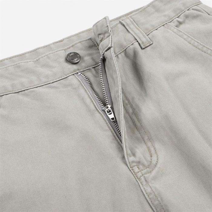Close-up of light gray cargo pants showing the button, belt loop, stitched waistband, and partially open zipper fly