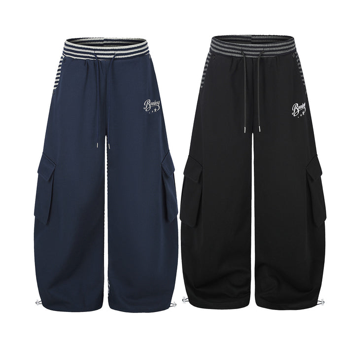Wide-leg cargo sweatpants in navy blue and black with striped waistband, flap cargo pockets, and embroidered logo