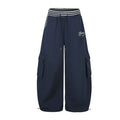 Front view of navy wide-leg cargo sweatpants with striped waistband, drawcord, side pockets and white script logo