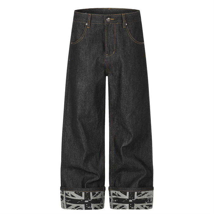 Front view of black wide-leg jeans with orange stitching, five-pocket styling, and gray rolled cuffs with flag print