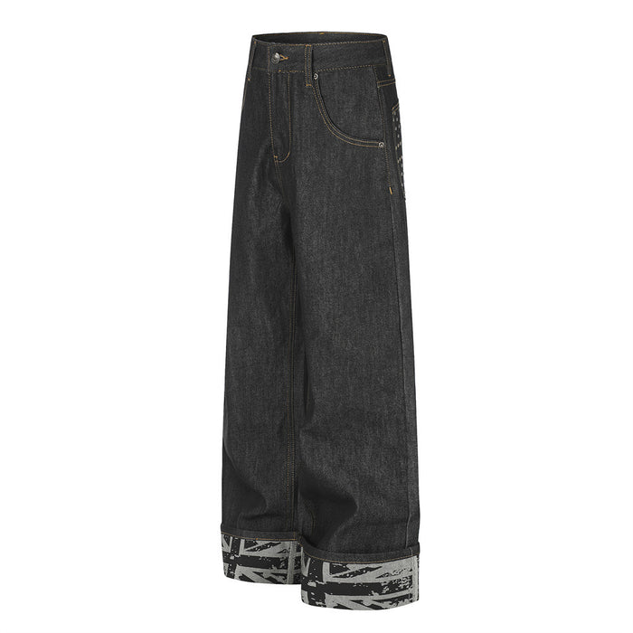 Angled side view of black wide-leg jeans showing the relaxed silhouette, curved front pocket, and printed rolled cuff
