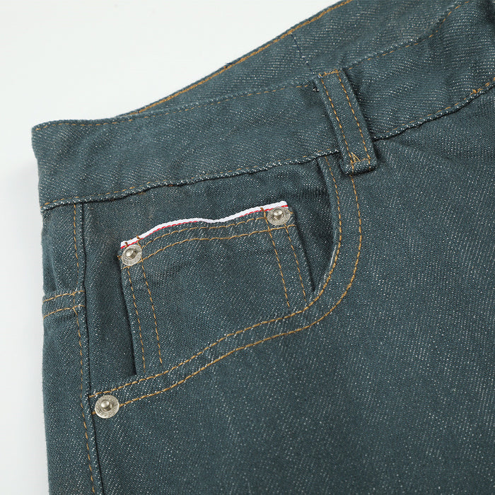 Close-up of a front pocket on teal green jeans with a small coin pocket, metal rivets, and contrast stitching