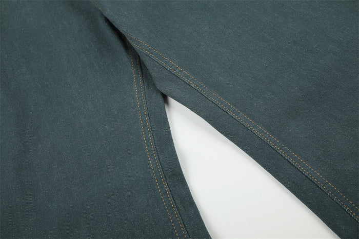 Close-up of the teal green jeans inner leg seam showing double rows of orange stitching