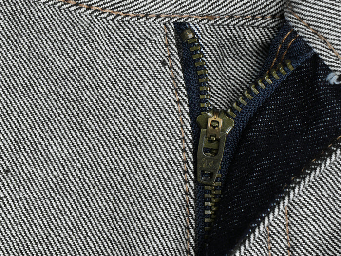 Close-up of the metal zipper and stitched gray denim fly on the wide-leg jeans