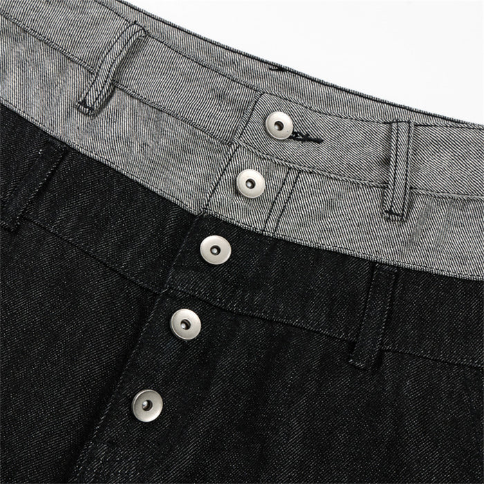 Detailed view of the gray waistband and silver button fly on black denim wide-leg jeans