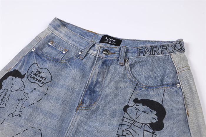 Close-up of the jeans front waistband, belt loops, button, pockets, and cartoon graphic details