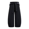 Black wide-leg pants shown from the front with a fold-over tie waistband, white lettering, and curved leg seams