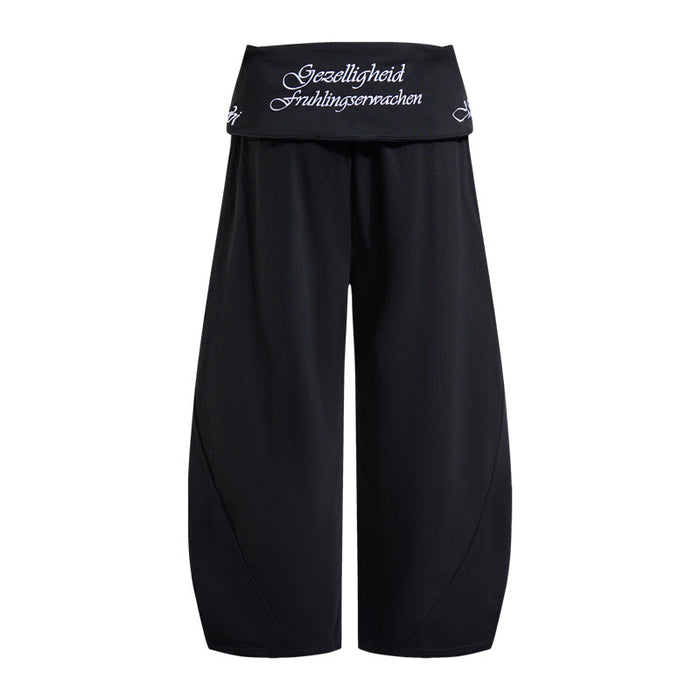 Black wide-leg pants shown from the back with a wide embroidered waistband and relaxed curved legs