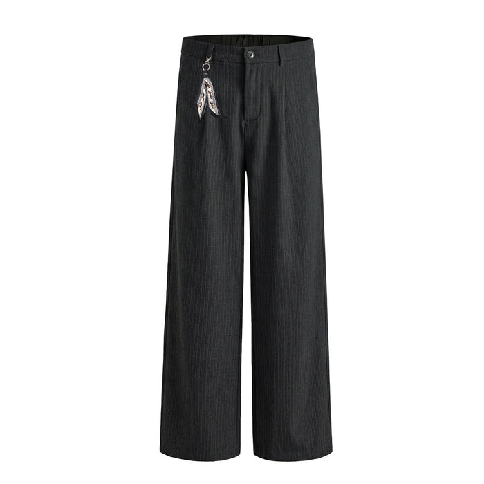 Front view of black pinstripe wide-leg trousers with pleated waist, button closure and patterned hanging charm