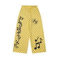 Wide-leg yellow polka dot sweatpants with music note and treble clef print and cursive script lettering on the leg