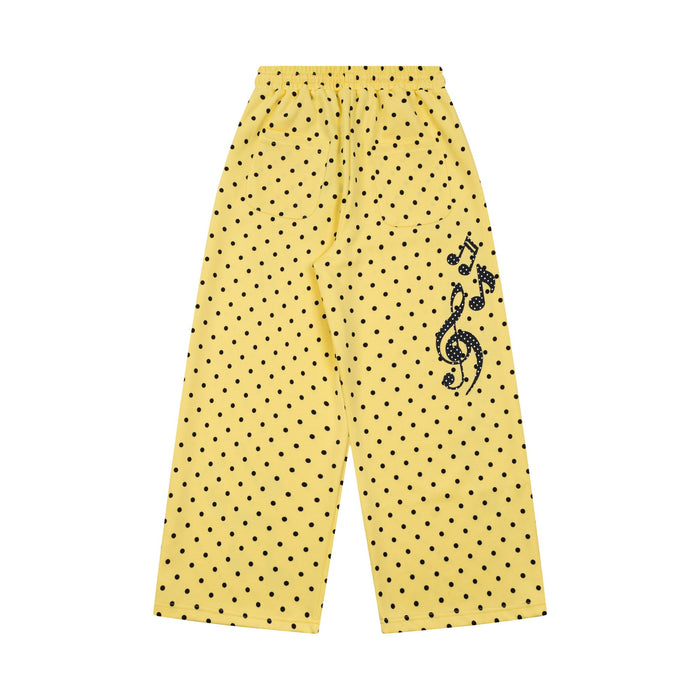 Yellow wide-leg sweatpants with black polka dots and a musical note treble clef graphic on the leg