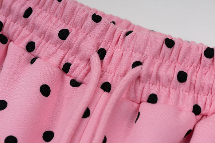 Detailed view of the elastic pink waistband, drawstring, and front pocket on polka dot sweatpants