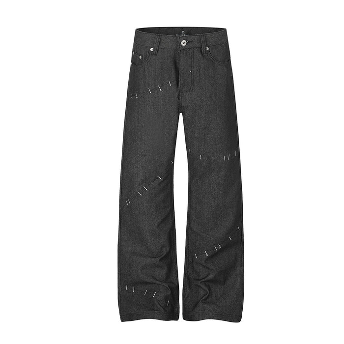 Black wide-leg raw denim jeans with deconstructed diagonal basting stitch detail, front view