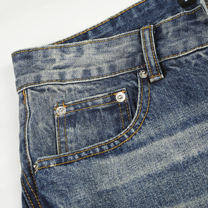 Close-up of the small front coin pocket with metal rivets and contrasting stitching on blue denim