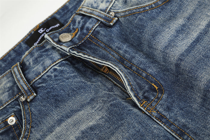 Close-up of the partially open jeans fly showing the metal button, zipper, and orange stitching