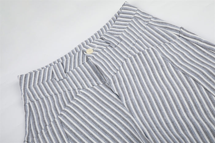 Close-up of the striped trouser waistband, front button, belt loops, and angled pocket opening