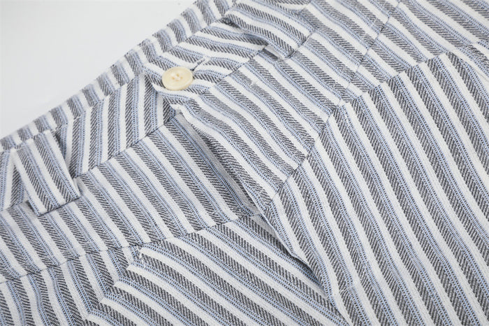 Detailed view of the high waistband, cream button, angled pocket seam, and gray-white striped fabric