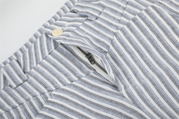 Close-up of the front fly showing a cream button and partially opened metal zipper on striped trousers