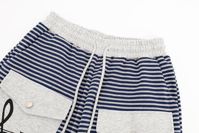 Close-up of the gray elastic waistband, white drawstring, navy stripes, and gray cargo pocket flap